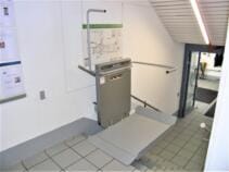 Der Treppenlift an der oberen Haltestelle, einseitig offen für Rollstuhlfahrer