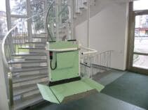 Ein Plattformlift über eine Treppe mit Kurve in einem Bürogebäude